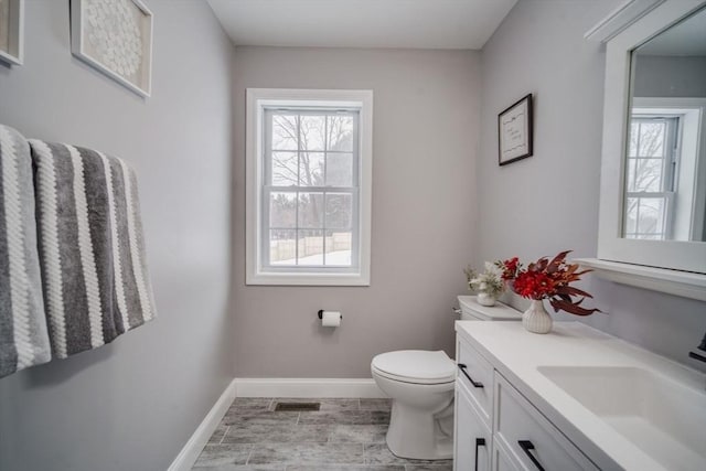 half bathroom with toilet, visible vents, baseboards, and vanity