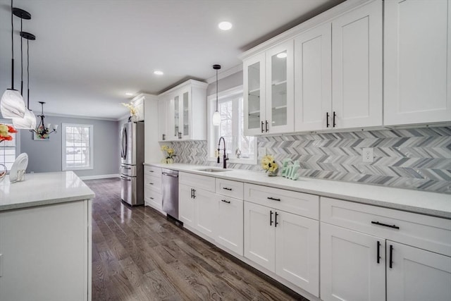 kitchen with stainless steel appliances, glass insert cabinets, light countertops, and decorative light fixtures