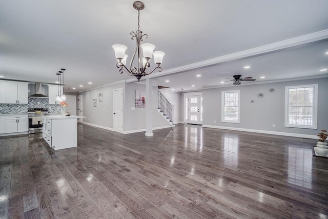 unfurnished living room with dark wood-style floors, baseboards, ornamental molding, and ceiling fan with notable chandelier