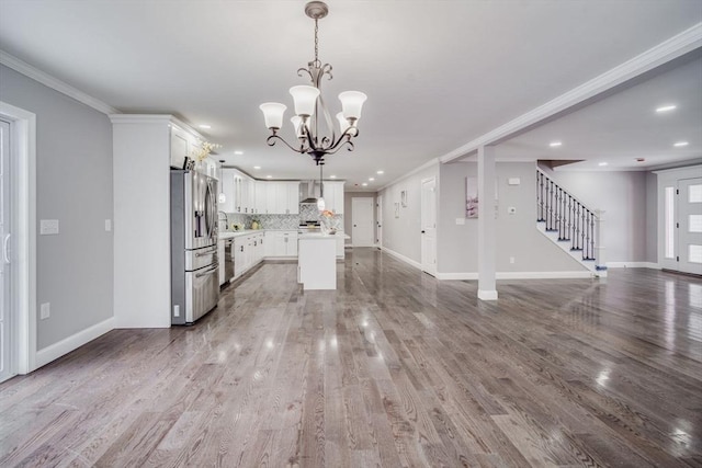 kitchen featuring pendant lighting, light countertops, appliances with stainless steel finishes, open floor plan, and white cabinetry