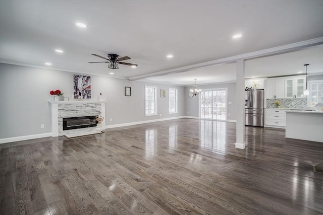 unfurnished living room featuring ornamental molding, a glass covered fireplace, and dark wood-style floors