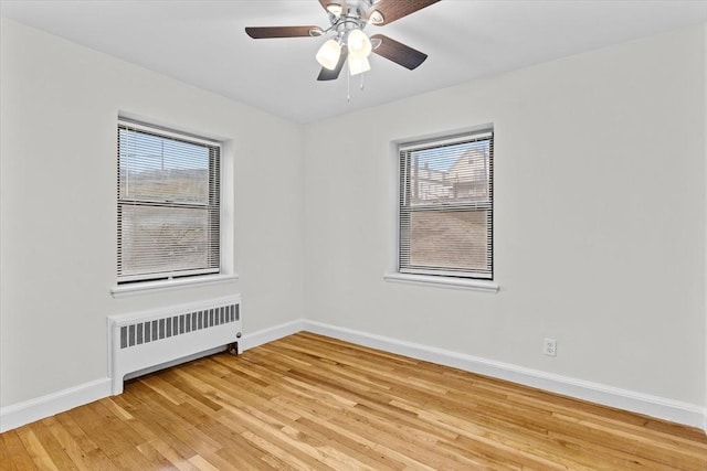 spare room with radiator heating unit, hardwood / wood-style flooring, and ceiling fan