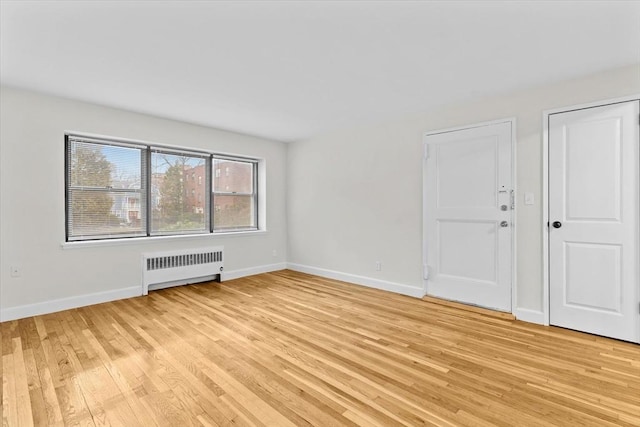 spare room with light wood-type flooring and radiator