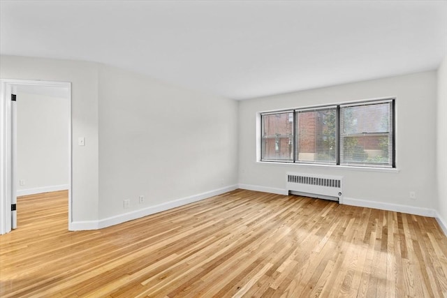 empty room featuring radiator heating unit and light hardwood / wood-style flooring