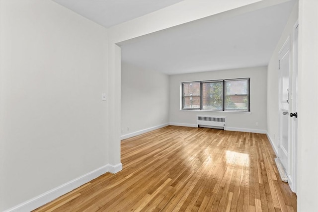 empty room with light wood-type flooring and radiator