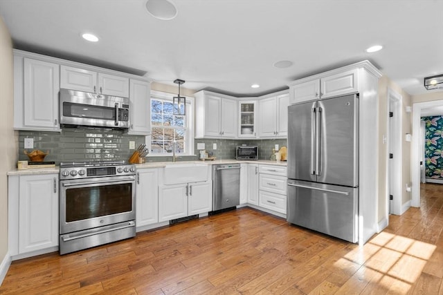 kitchen with pendant lighting, decorative backsplash, white cabinetry, appliances with stainless steel finishes, and sink