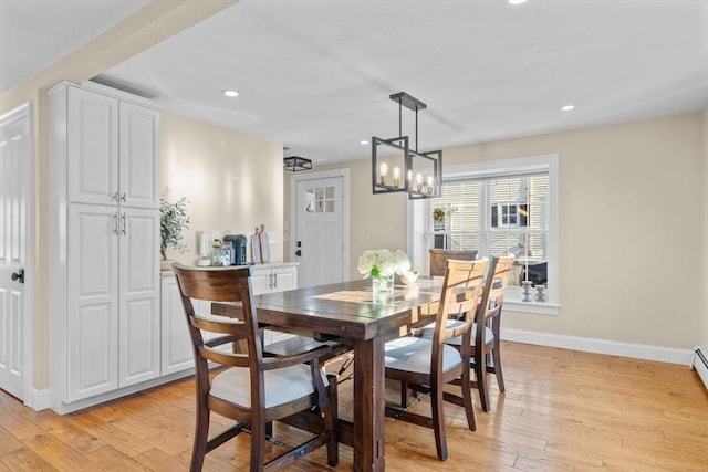 dining space with light hardwood / wood-style floors and an inviting chandelier