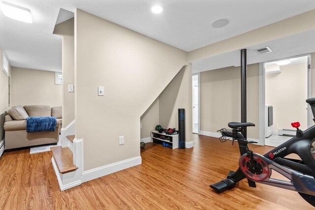 workout area with a baseboard heating unit and light hardwood / wood-style floors