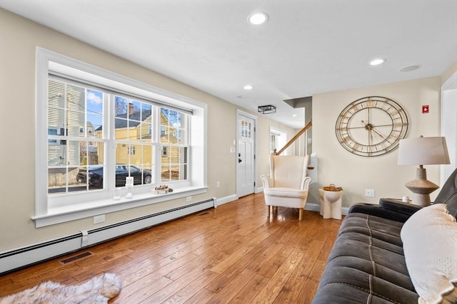 living room with a baseboard heating unit and wood-type flooring