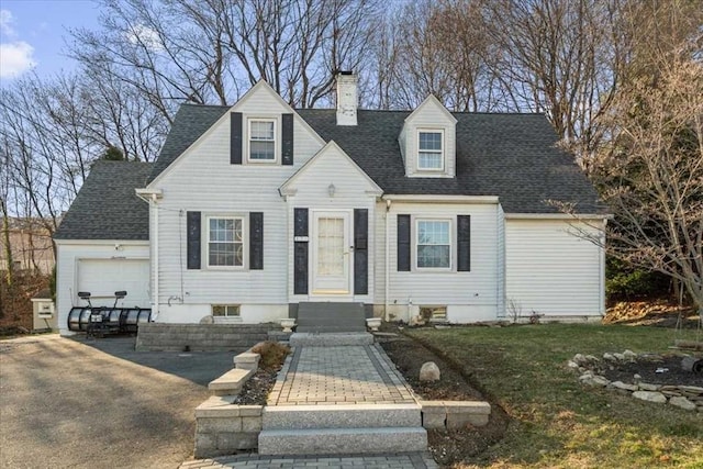 cape cod-style house featuring a front yard and a garage