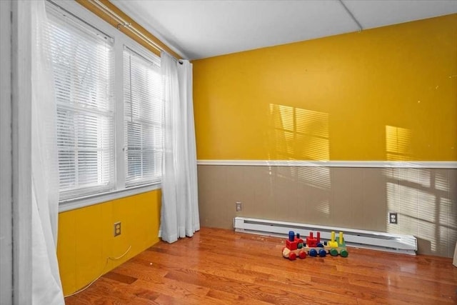 rec room with wood-type flooring and baseboard heating