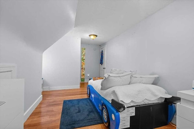 bedroom with lofted ceiling and wood-type flooring