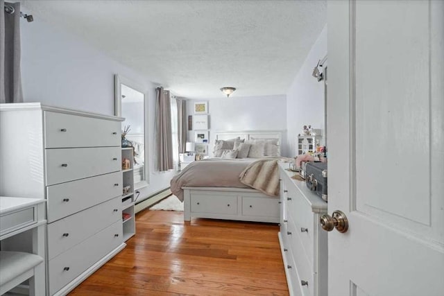 bedroom featuring light hardwood / wood-style flooring and a baseboard heating unit