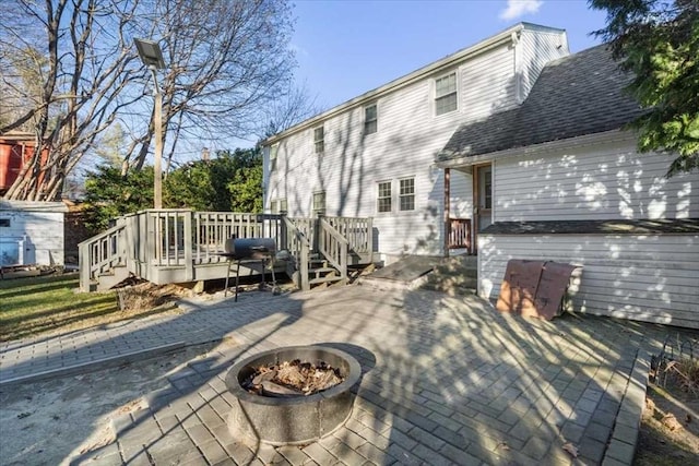 rear view of property featuring a fire pit, a deck, and a patio