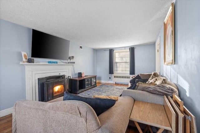 living room with hardwood / wood-style floors, a textured ceiling, and radiator