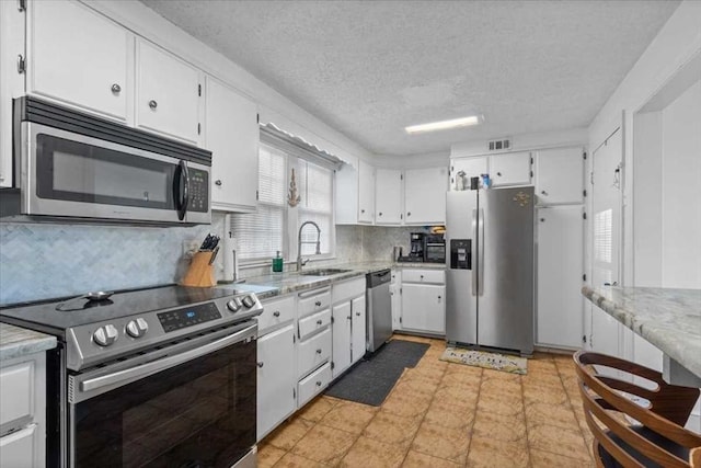 kitchen featuring backsplash, white cabinets, sink, a textured ceiling, and stainless steel appliances