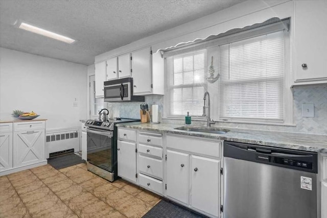 kitchen with backsplash, radiator heating unit, sink, appliances with stainless steel finishes, and white cabinetry