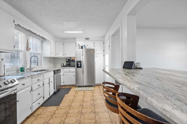 kitchen with white cabinets, sink, appliances with stainless steel finishes, and a textured ceiling