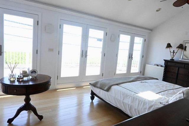 bedroom featuring french doors, vaulted ceiling, and light wood-type flooring