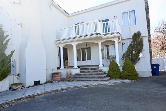 view of exterior entry featuring a balcony and a porch