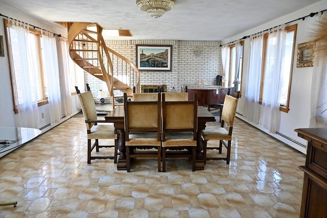 dining room featuring a baseboard radiator, brick wall, and a notable chandelier