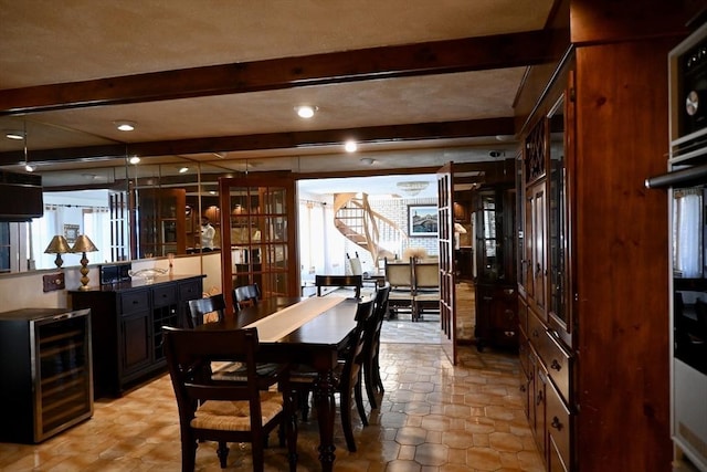 dining space featuring beamed ceiling and beverage cooler