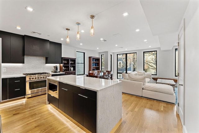 kitchen featuring appliances with stainless steel finishes, modern cabinets, dark cabinets, tasteful backsplash, and recessed lighting