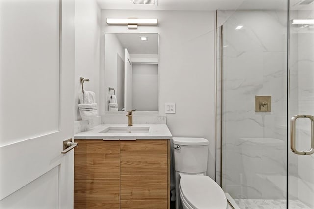 bathroom with toilet, a marble finish shower, and vanity