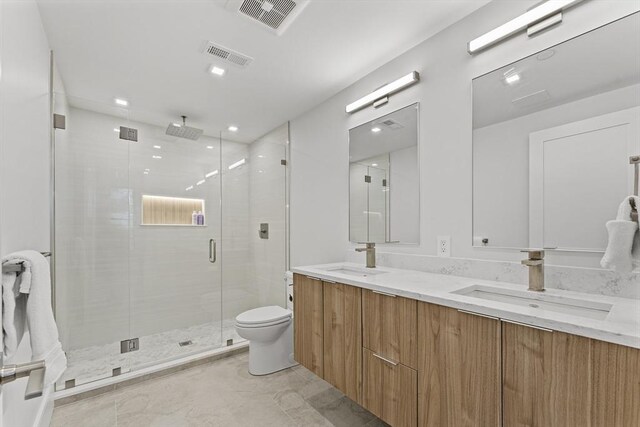 full bathroom with a stall shower, toilet, double vanity, and marble finish floors