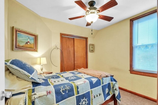 carpeted bedroom with ceiling fan, a closet, and vaulted ceiling