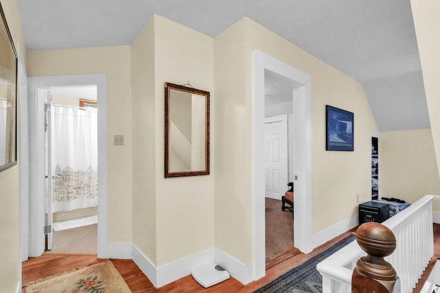 hallway with light hardwood / wood-style floors and vaulted ceiling