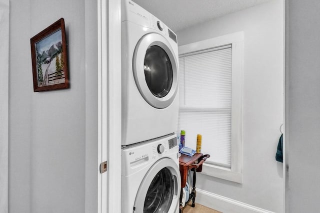 clothes washing area featuring a textured ceiling and stacked washer / drying machine