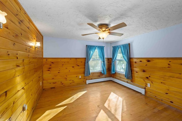 additional living space with light wood finished floors, wainscoting, and wooden walls