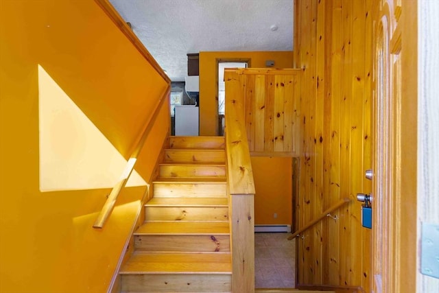 stairway with a baseboard heating unit and a textured ceiling