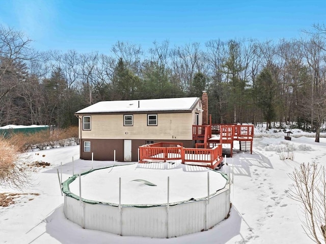 snow covered back of property featuring a chimney and a wooden deck