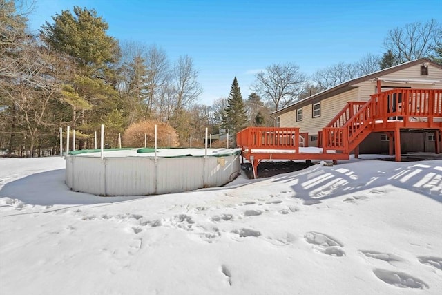 yard layered in snow with an outdoor pool and a deck