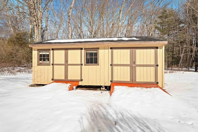 snow covered structure with an outbuilding