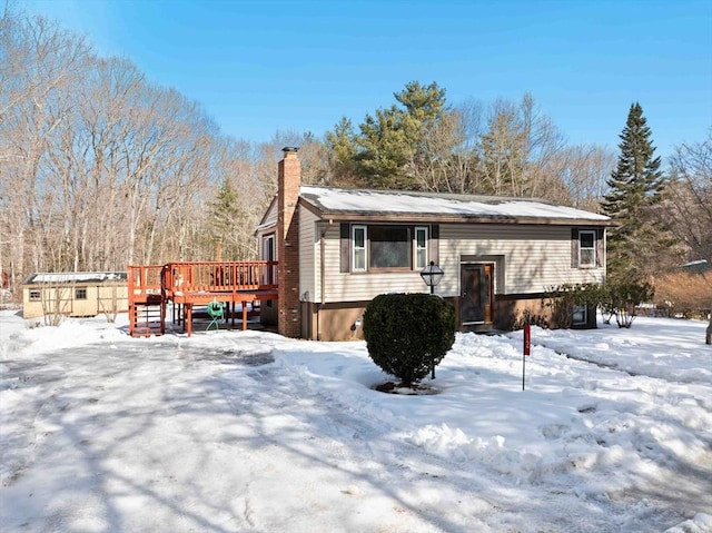 bi-level home with a chimney and a wooden deck