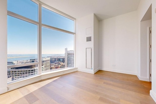 unfurnished room featuring a water view and light hardwood / wood-style flooring