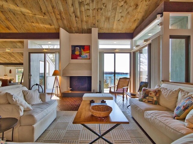 living area with wooden ceiling, a fireplace with raised hearth, and brick floors