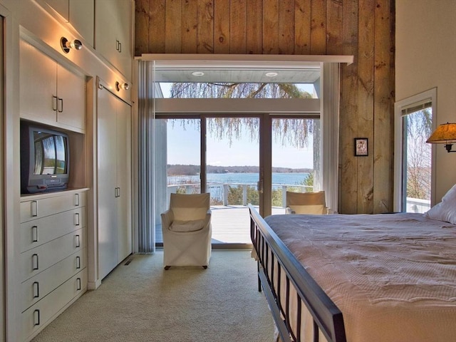 bedroom with a water view, light colored carpet, and multiple windows