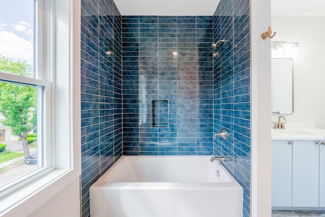 bathroom featuring vanity, tiled shower / bath, and a healthy amount of sunlight