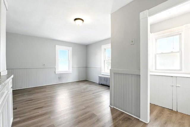 spare room featuring radiator heating unit, wood finished floors, plenty of natural light, and wainscoting