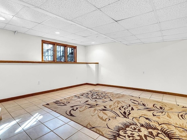 unfurnished room with a paneled ceiling and light tile patterned flooring