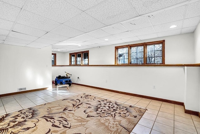 tiled empty room featuring a paneled ceiling