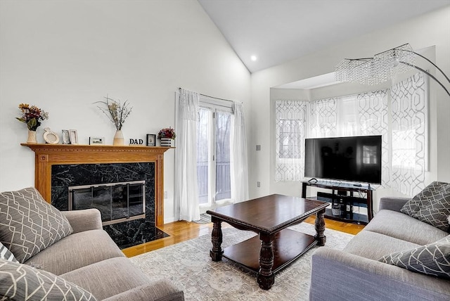 living room with light hardwood / wood-style floors, high vaulted ceiling, and a high end fireplace