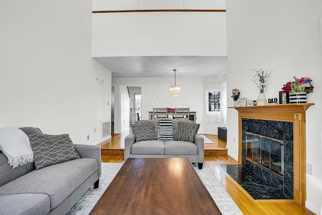 living room featuring a premium fireplace, a chandelier, and wood-type flooring