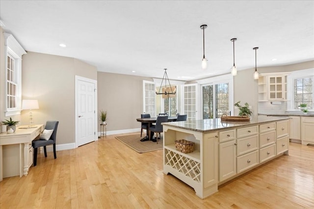 kitchen with hanging light fixtures, light wood-style floors, a kitchen island, and open shelves