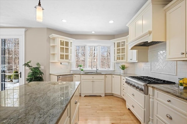 kitchen featuring backsplash, light wood-style floors, a sink, gas cooktop, and premium range hood