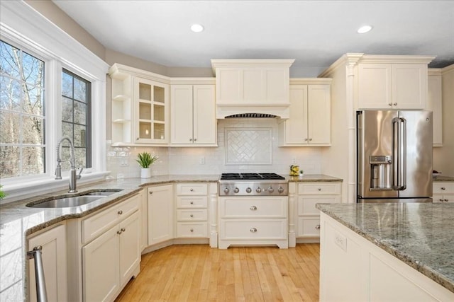 kitchen featuring light wood finished floors, backsplash, stainless steel appliances, and a sink